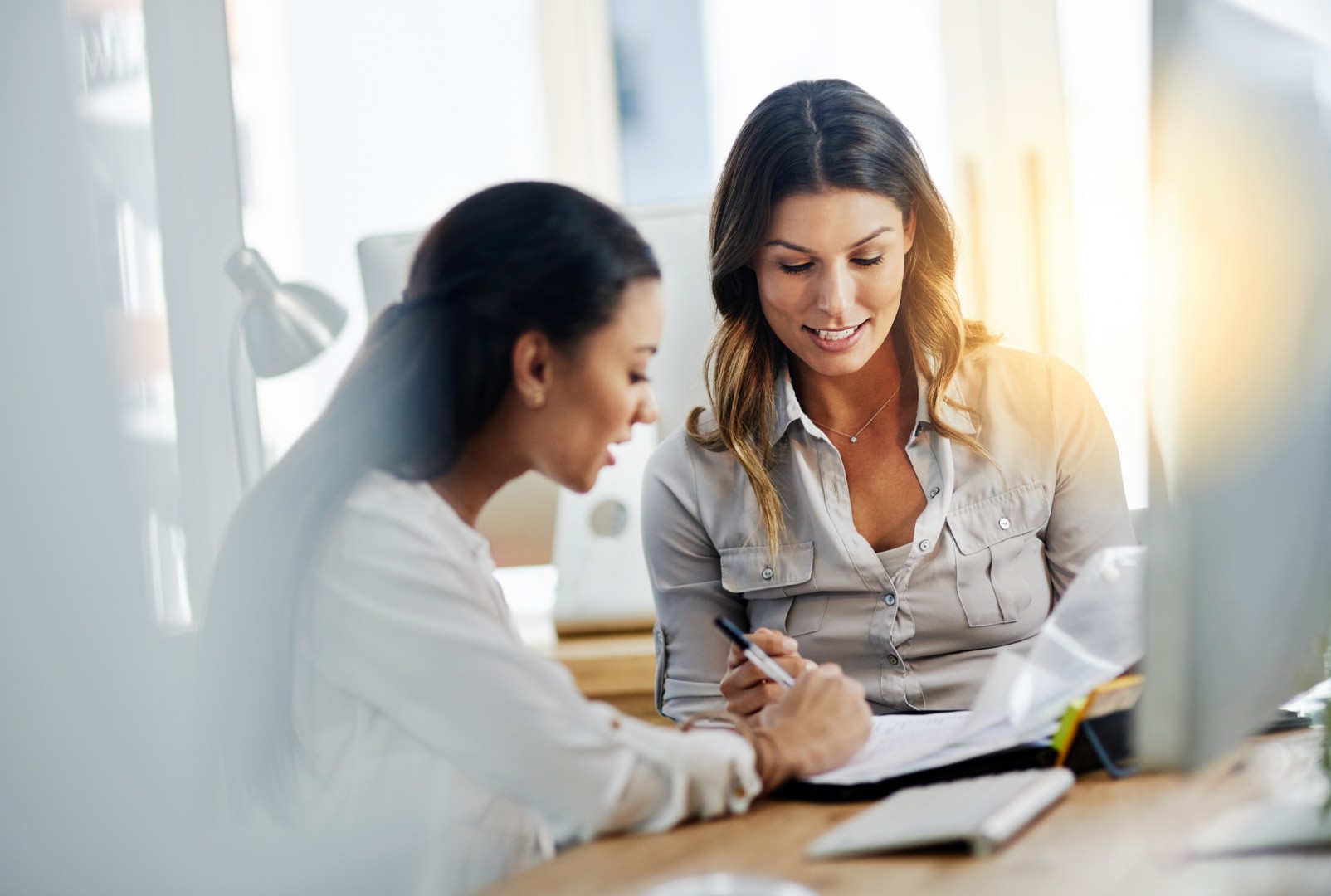 Two women around a contract with one signing it